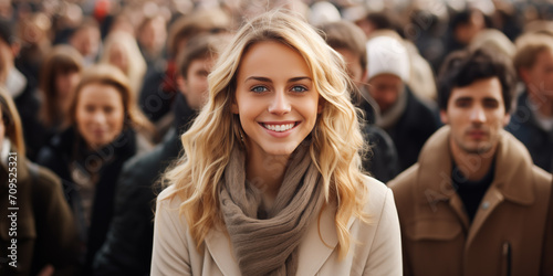 Beautiful blonde woman is smiling in front of large crowd of people, 