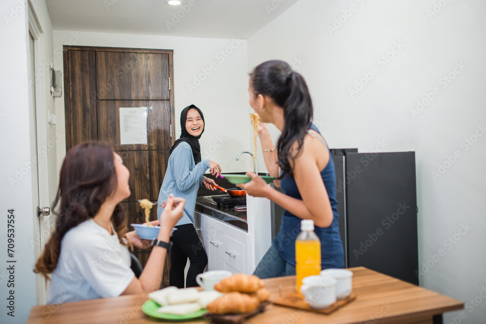 hijab girl laughs while cooking for breakfast with friends in the kitchen