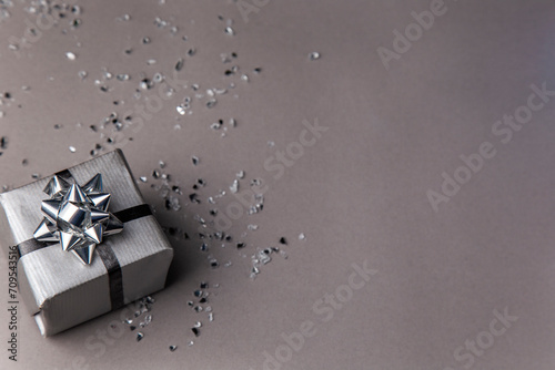 grey gift box with silver ribbon on a grey background with copy space for text.