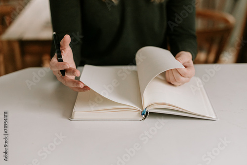 Woman's hands flipping through empty notebook journal at home