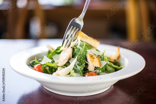 childs small portion of a chicken caesar salad with a small fork