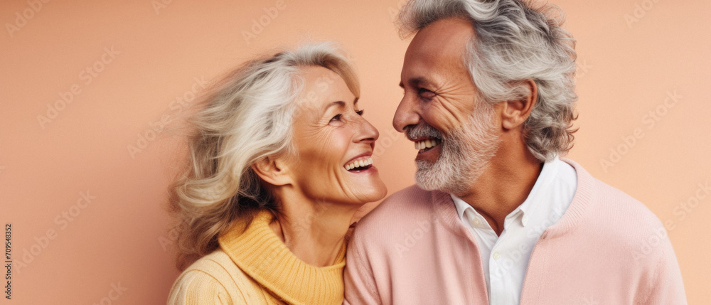 Happy senior couple hugging and looking at each other isolated on beige.