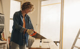 Skilled woman using a saw to cut wood for baseboards in an interior kitchen remodel
