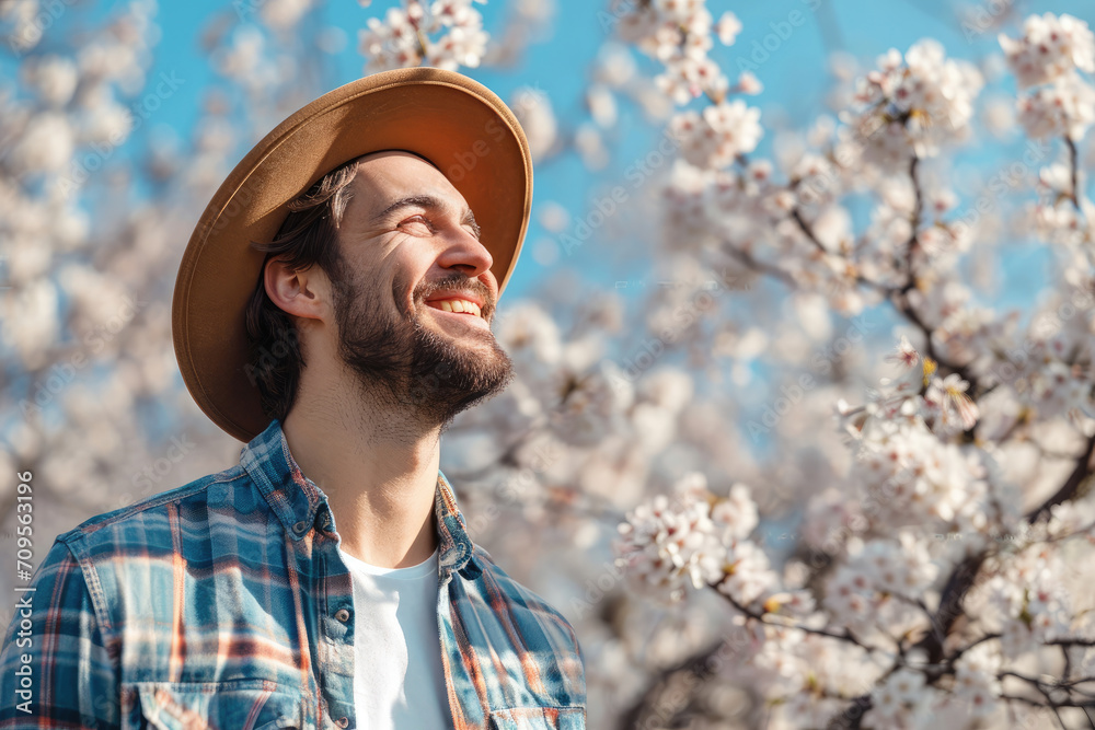 Obraz premium Smiling man enjoying warm spring day on background of blooming cherry trees