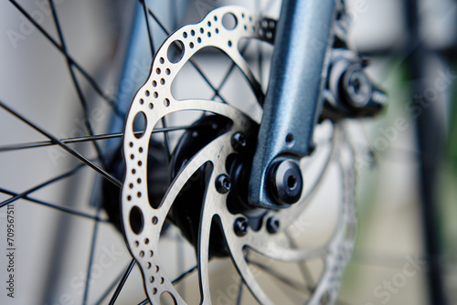 Part of the bicycle's braking system. Grey metal brake disc and brake pads on road bike, close up. photo