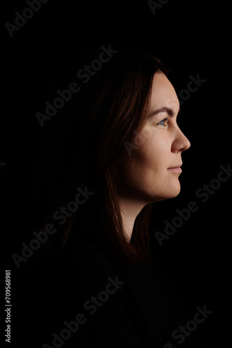 Side view portrait of a lovely woman on dark background