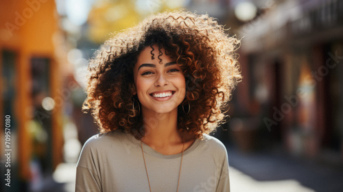 Portrait of a smiling young woman with curly hair in the city