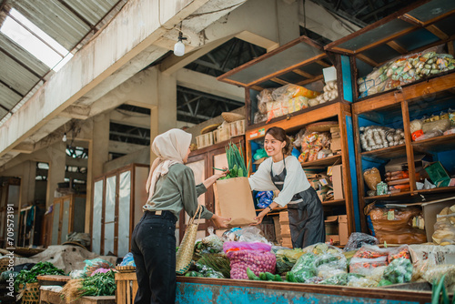 Slika na platnu female asian green grocery seller giving customer vegetables in paperbag