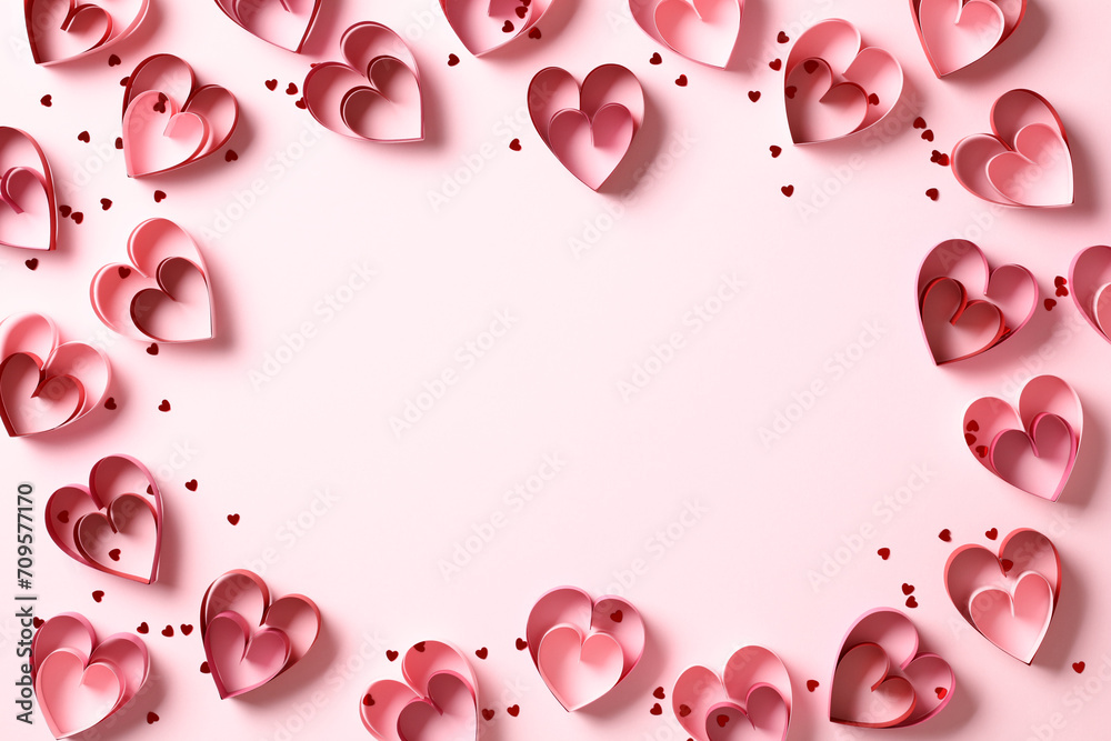Saint Valentine Day frame of red paper cut hearts on pink background. Flat lay, top view, copy space.