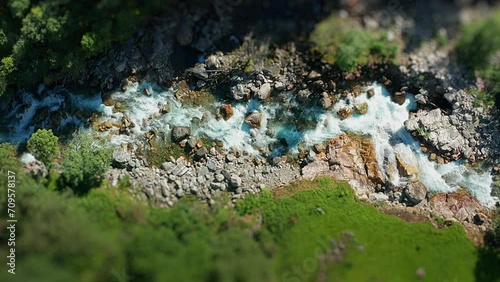 Mountain river rushes through the deep rocky canyon. Green trees on the canyon sides. Aerial view. Tilt-shift. photo