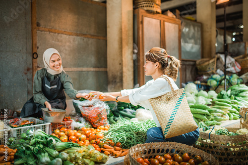 greengrocery seller receiving vegetables that customer buying from her