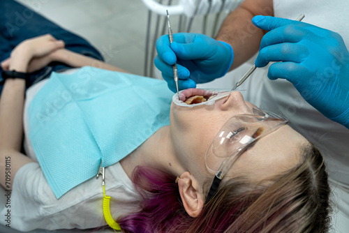 Professional male and female dentists treat a woman s teeth in a dental office.