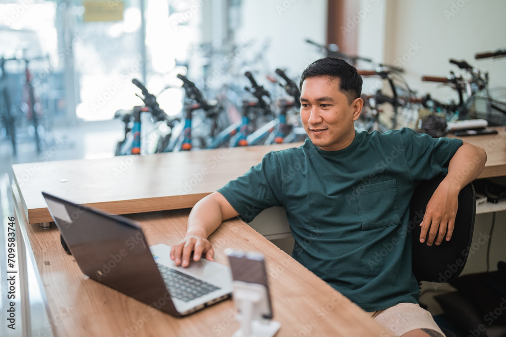handsome young man using a laptop computer while working in a store
