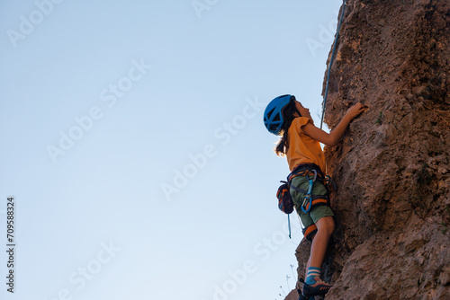 climber boy. the child trains in rock climbing. cute teen kid climbing on rock with insurance, lifestyle sport people concept.