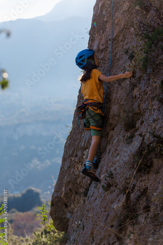 climber boy. the child trains in rock climbing. cute teen kid climbing on rock with insurance  lifestyle sport people concept.