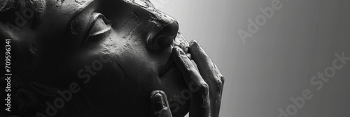 classic sculpture of a person's head looking up, searching for answers and inspiration, hand touching lips, grey background with some copy space, closeup photo