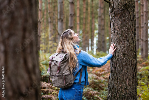 Happy woman touching tree trunk in Cannock chase forest