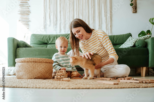 Mother and son with cat playing in the living room at home photo