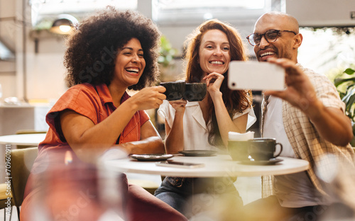 Group of happy friends taking selfies and making memories over coffee photo