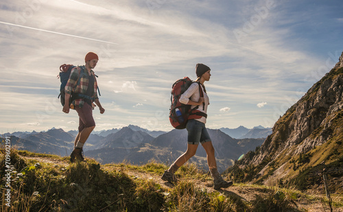 Young backpackers hiking on mountain trail in Tannheimer Tal, Tyrol, Austria photo