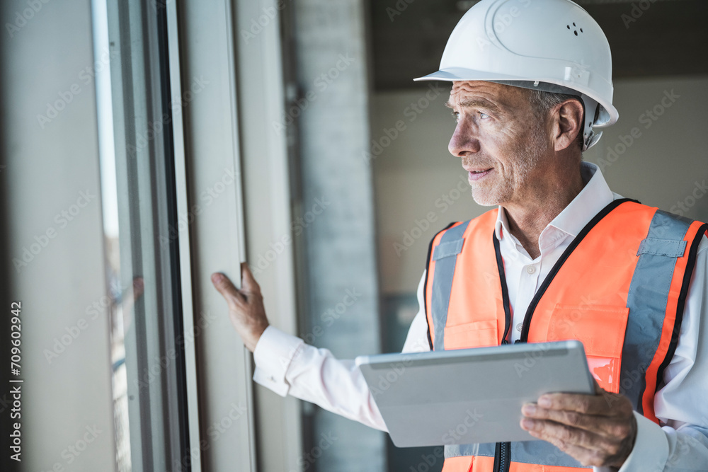 Engineer holding tablet PC and looking through window Engineer holding tablet PC and looking through window