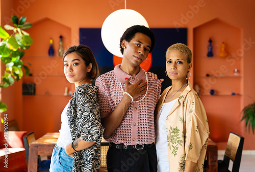 Group of friends bonding at home, LGBTQ and diversity concepts - Homosexual couple and fluid gender non binary young man with LGBT cross dressing clothing style having fun in the apartment photo