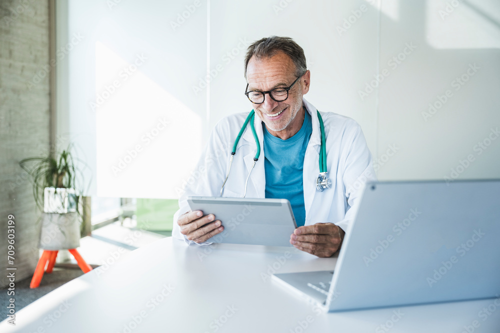 Happy doctor talking on video call through tablet PC at desk Happy doctor talking on video call through tablet PC at desk
