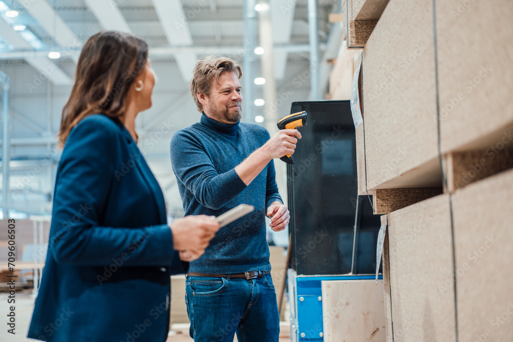 Smiling businessman scanning bar code on wooden plank by colleague in industry Smiling businessman scanning bar code on wooden plank by colleague in industry