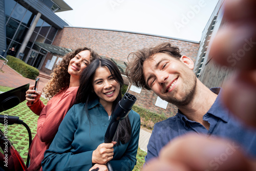 Young man taking selfie with friends at charging station photo