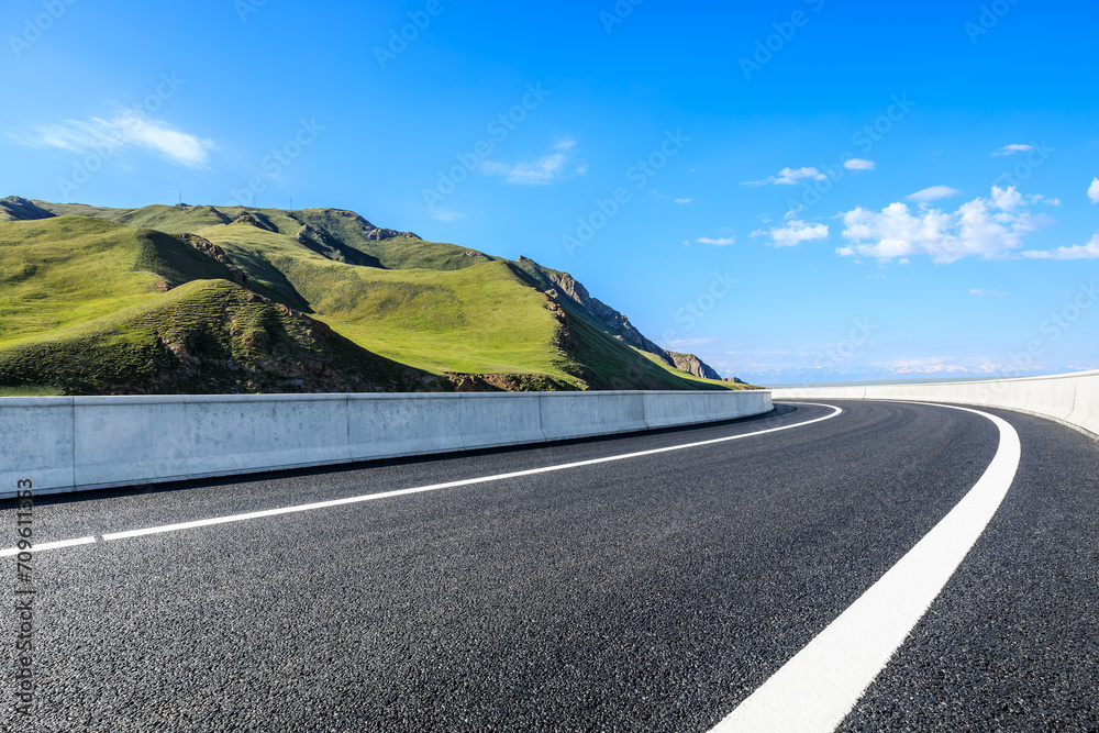 Asphalt highway road and green mountain nature landscape under blue sky - obrazy, fototapety, plakaty 