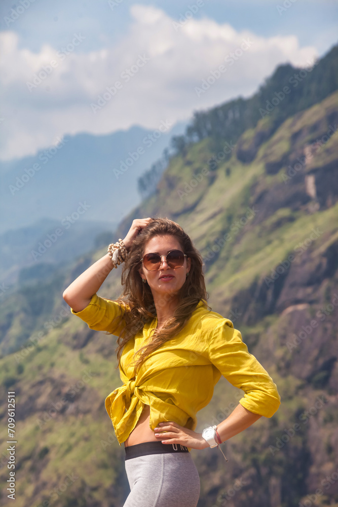 Lovely adult lady posing at Sri Lanka Adam's peak mountain in sight, landmark nature, looking at camera. Pretty woman in sunglasses enjoying at tropical journey, Ella, Sri Lanka. Copy ad text space