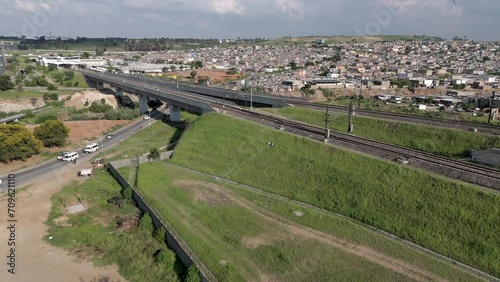 In this concise 4K aerial footage, a rising drone captures the urban landscape of a township adjacent to the Gautrain railways and highways in Johannesburg, South Africa. photo