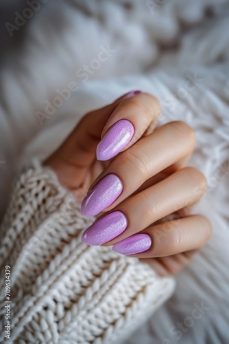 A close-up shot of a woman's hand holding a perfectly manicured purple nail. This image can be used in beauty and fashion-related projects