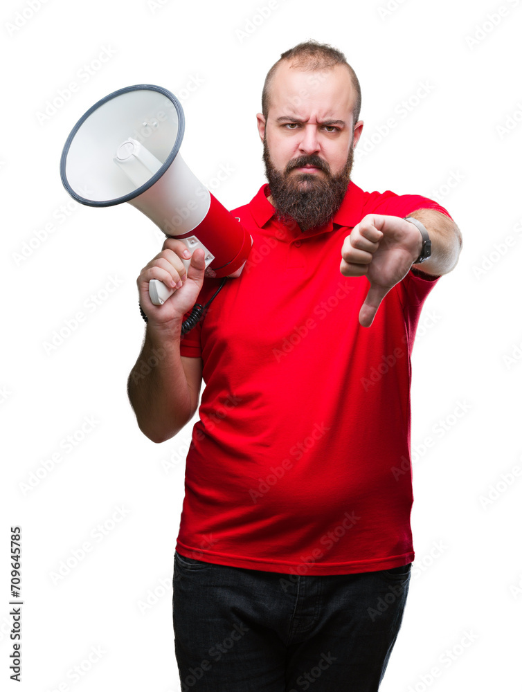 Young caucasian man shouting through megaphone over isolated background with angry face, negative sign showing dislike with thumbs down, rejection concept Young caucasian man shouting through megaphone over isolated background with angry face, negative sign showing dislike with thumbs down, rejection concept