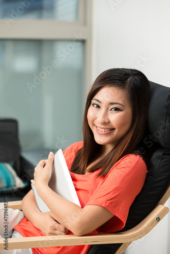 Asian woman at home reading a tablet PC.