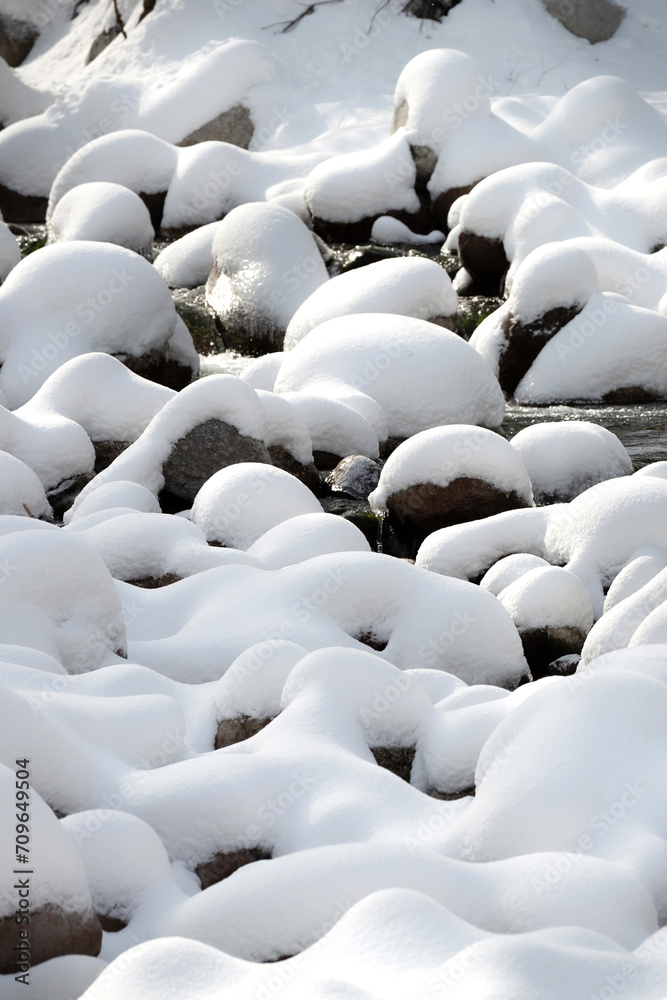 Obraz premium Winter landscape with snow-covered stones at the river