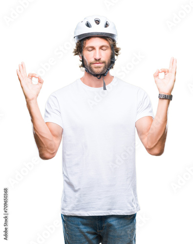Handsome hispanic cyclist man wearing safety helmet over isolated background relax and smiling with eyes closed doing meditation gesture with fingers. Yoga concept.