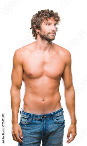 Handsome hispanic model man sexy and shirtless over isolated background looking away to side with smile on face, natural expression. Laughing confident.