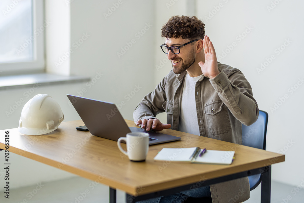 Obraz premium Successful young man looking on laptop video call while working at home office