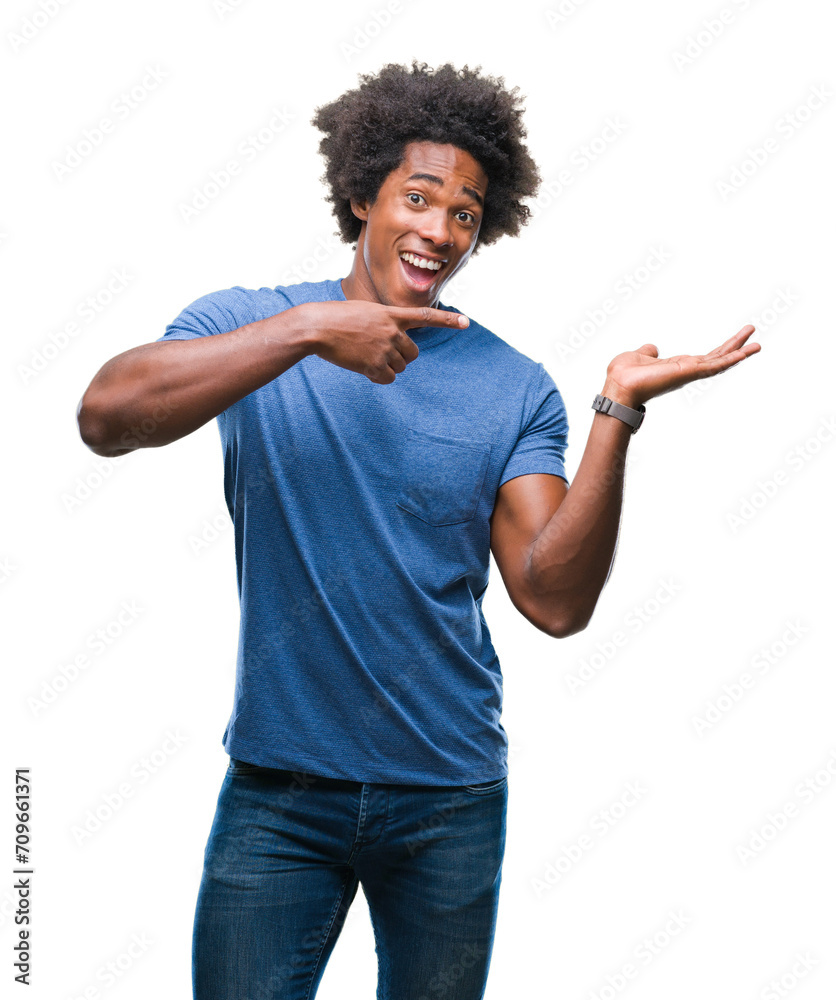 Afro american man over isolated background amazed and smiling to the camera while presenting with hand and pointing with finger. Afro american man over isolated background amazed and smiling to the camera while presenting with hand and pointing with finger.