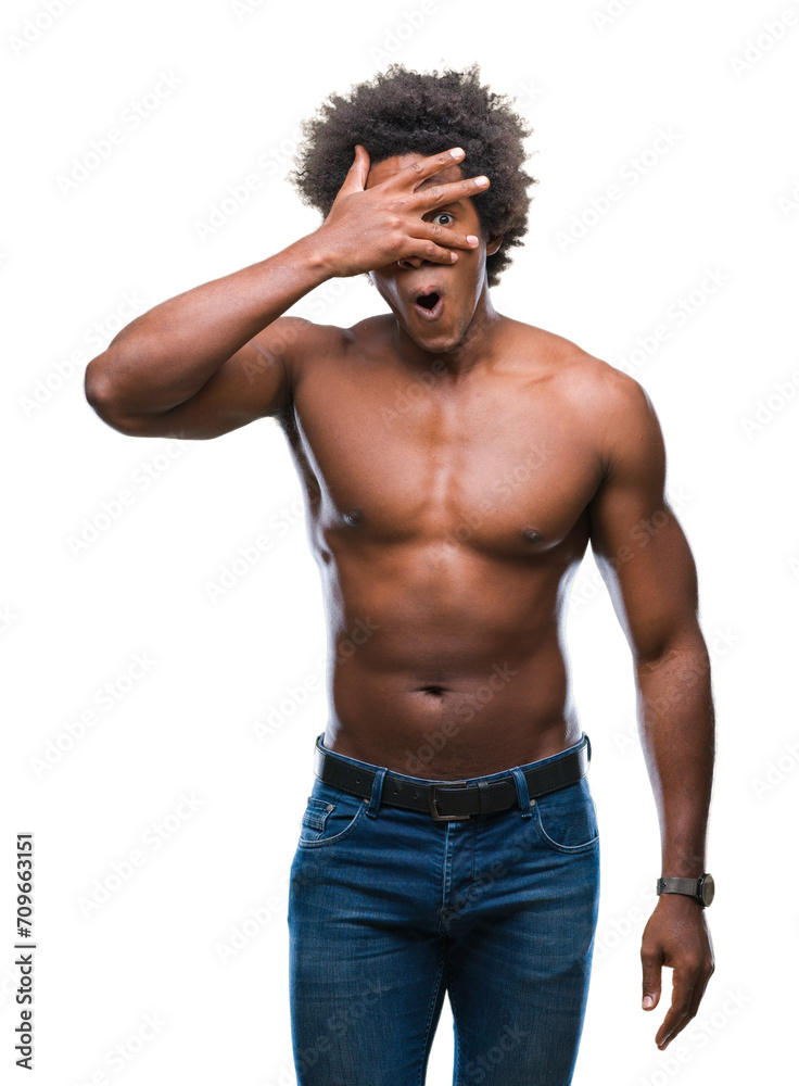 Afro american shirtless man showing nude body over isolated background peeking in shock covering face and eyes with hand, looking through fingers with embarrassed expression. Afro american shirtless man showing nude body over isolated background peeking in shock covering face and eyes with hand, looking through fingers with embarrassed expression.