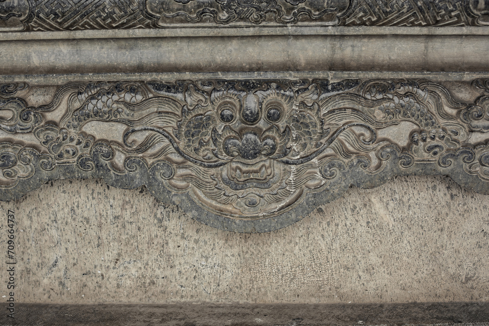 Intricate dragon in cloud carvings on ancient stone stele at historical Tomb of Khai Dinh site, Vietnam