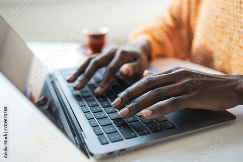 Anonymous female freelancer typing on laptop in home office photo