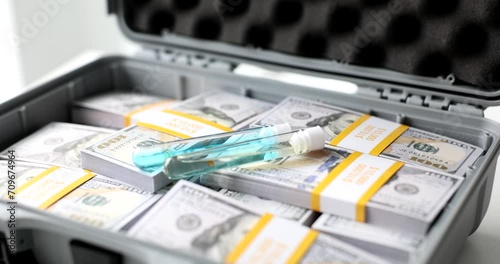 Test tubes with blue liquid vaccine or poison in suitcase with dollars. Selling illegal toxic substance drugs photo