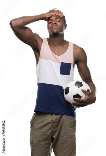 Young african american man holding soccer football ball stressed with hand on head, shocked with shame and surprise face, angry and frustrated. Fear and upset for mistake. © Krakenimages.com