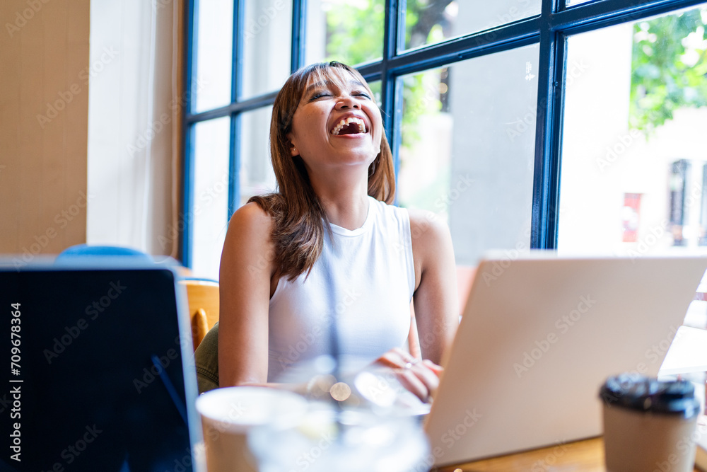 Cheerful Asian woman enjoying a remote work session in a cafe, with a bright window backdrop in Chiang Mai, Thailand Cheerful Asian woman enjoying a remote work session in a cafe, with a bright window backdrop in Chiang Mai, Thailand