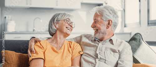 Happy laughing older married couple talking, laughing, standing in home interior together, hugging with love, enjoying close relationships, trust, support, care, feeling joy, tenderness. photo