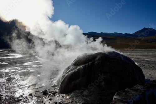 Steam rising from a bolder geyser at The Geysers Del Tatio, Antofagasta, Chile, with blue skies behind. 