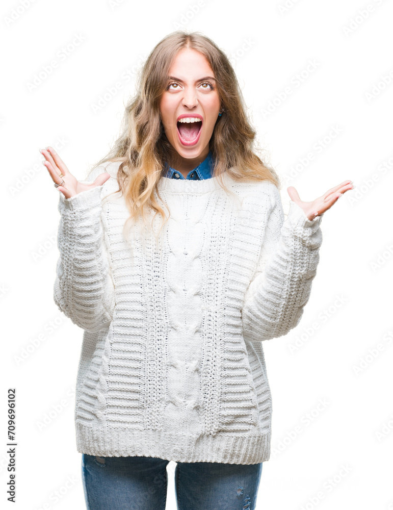 Beautiful young blonde woman wearing winter sweater over isolated background crazy and mad shouting and yelling with aggressive expression and arms raised. Frustration concept. Beautiful young blonde woman wearing winter sweater over isolated background crazy and mad shouting and yelling with aggressive expression and arms raised. Frustration concept.