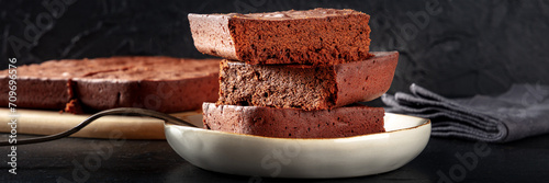 фотографія Chocolate brownie panorama, simple coffee cake, a side view on a black backgroun